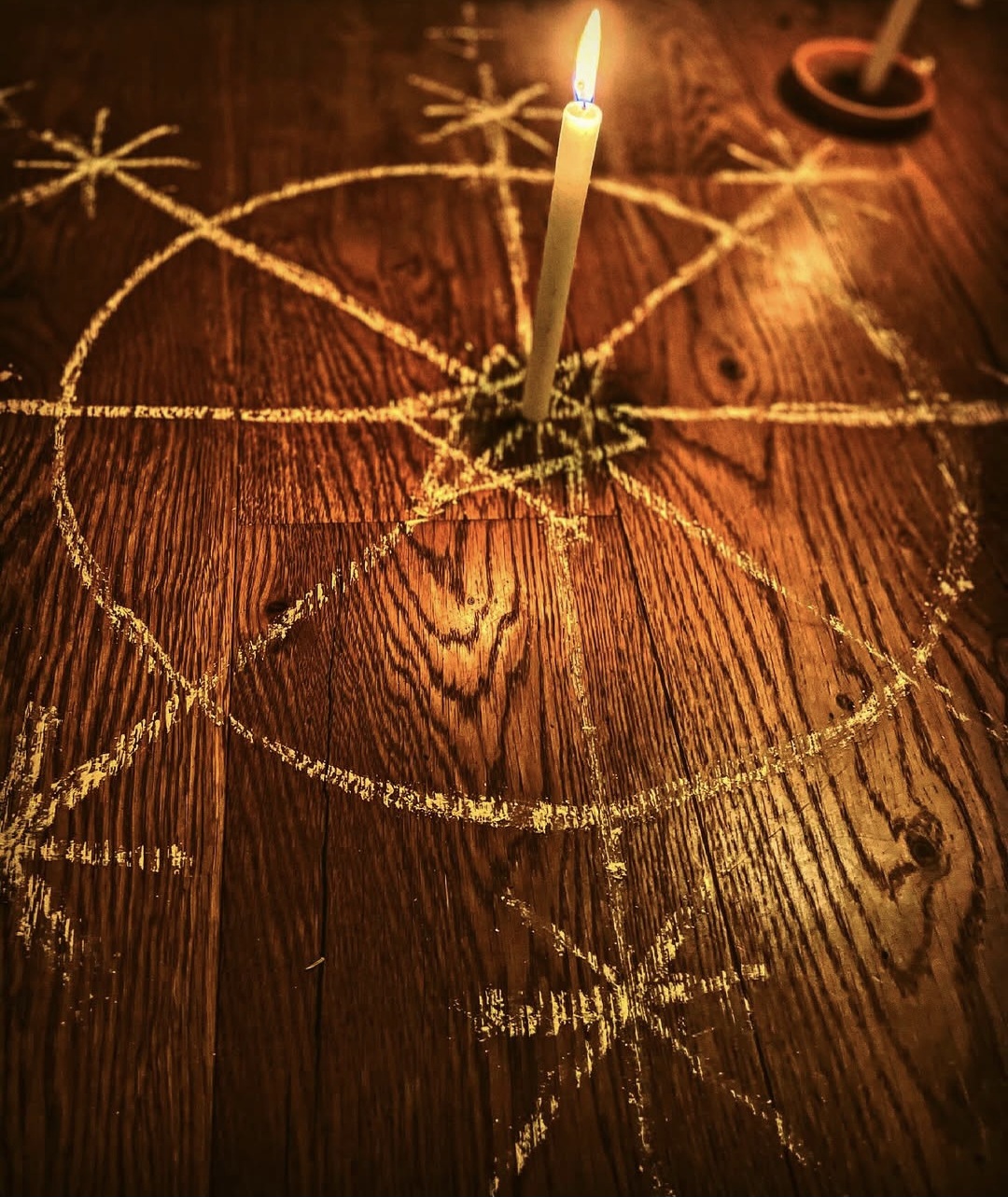 A Ponto Riscado traced in chalk on a wooden floor, lit by a single candle